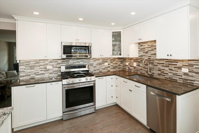 kitchen featuring white cabinets, decorative backsplash, stainless steel appliances, and a sink