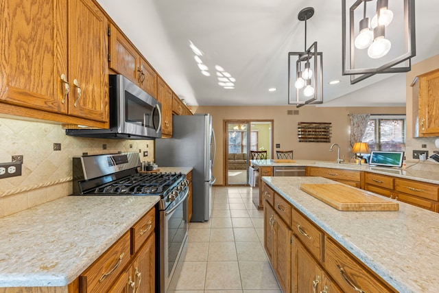 kitchen featuring brown cabinets, light tile patterned floors, backsplash, appliances with stainless steel finishes, and a sink