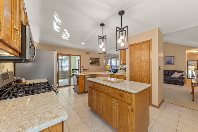 kitchen with stainless steel appliances, brown cabinetry, light tile patterned flooring, a kitchen island, and a peninsula