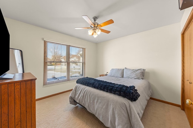 bedroom featuring light carpet, a closet, baseboards, and a ceiling fan