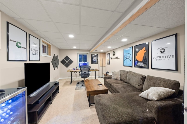 living area with baseboards, a drop ceiling, and recessed lighting