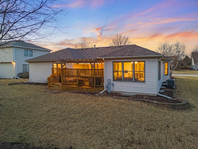 rear view of property featuring a deck, central AC, a yard, roof with shingles, and a pergola