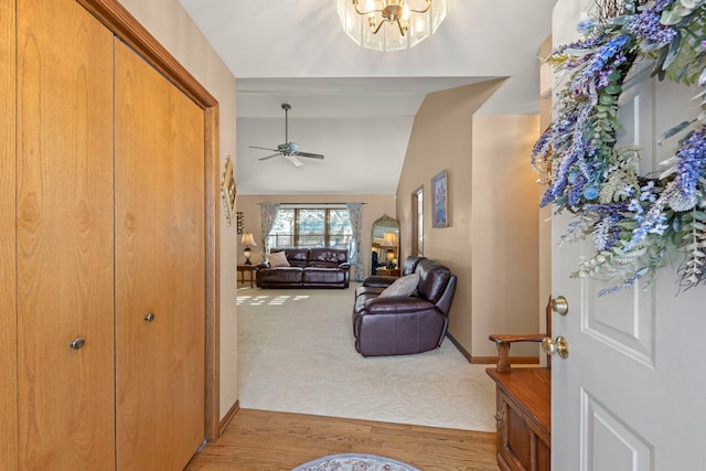 carpeted entryway with vaulted ceiling, wood finished floors, a ceiling fan, and baseboards