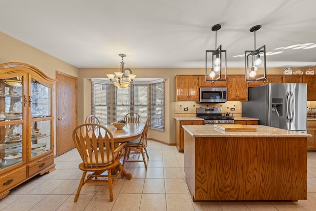 kitchen with a center island, stainless steel appliances, hanging light fixtures, decorative backsplash, and brown cabinetry