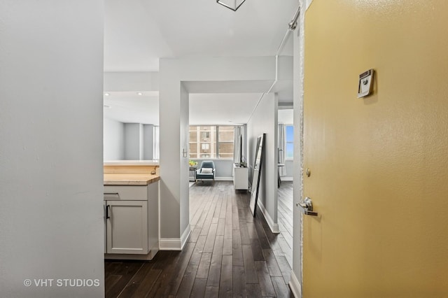 hallway with dark wood-type flooring and baseboards