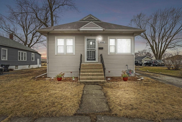 bungalow with entry steps and a yard