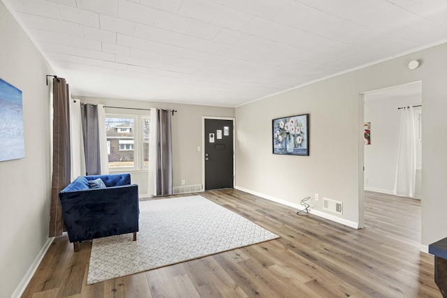 entrance foyer featuring baseboards, crown molding, visible vents, and wood finished floors