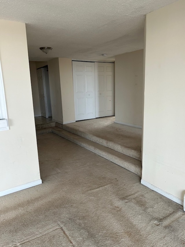 interior space with carpet floors, a textured ceiling, and baseboards