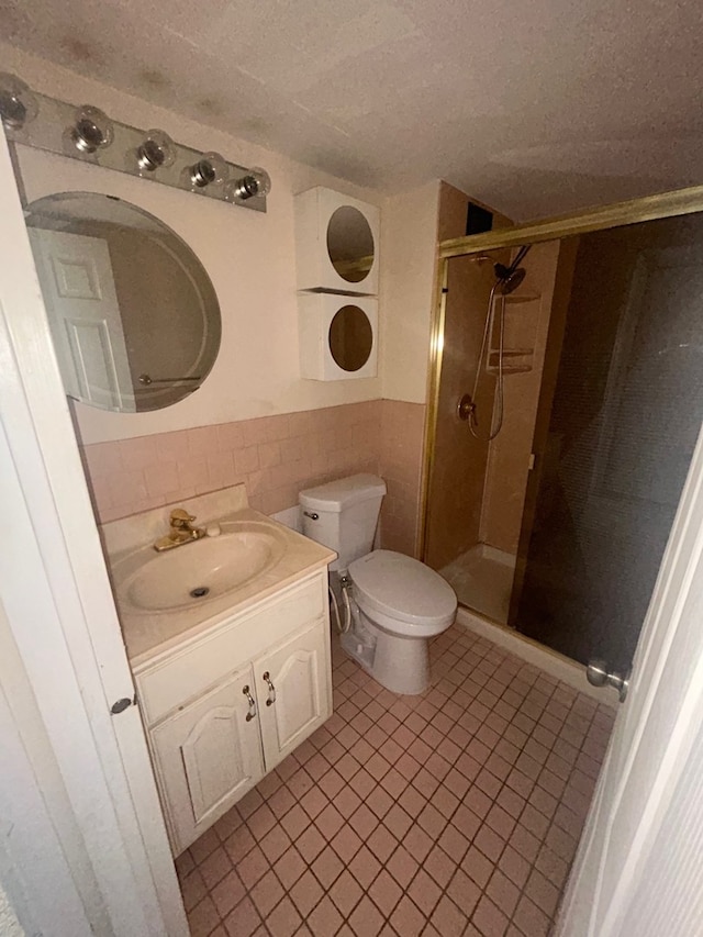 full bath featuring a stall shower, toilet, a textured ceiling, vanity, and tile walls