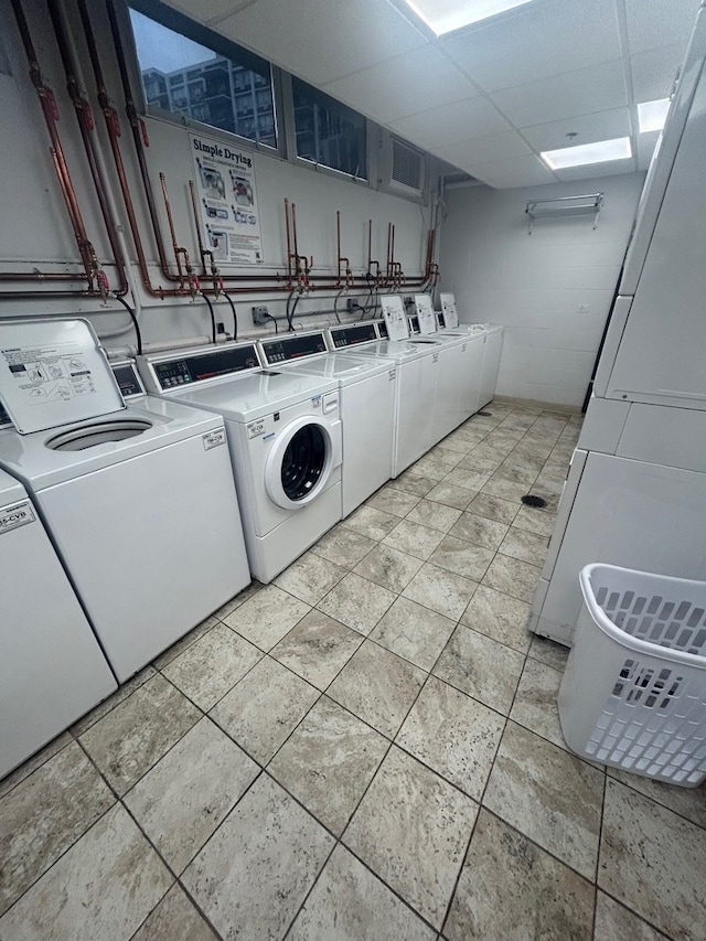 community laundry room with concrete block wall and washing machine and clothes dryer