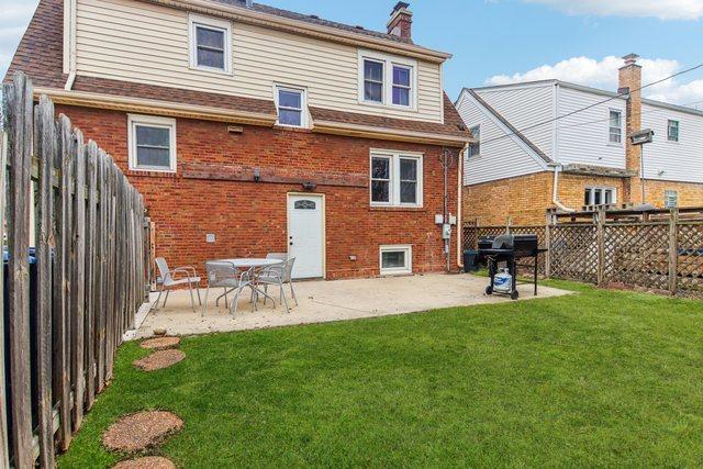 rear view of property featuring a yard, brick siding, a patio, and a fenced backyard