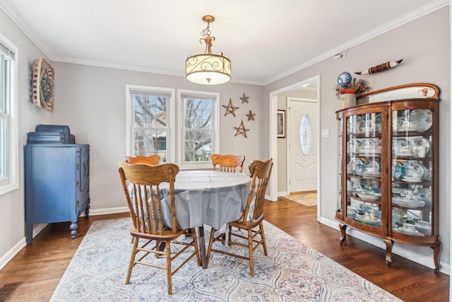 dining space featuring baseboards, wood finished floors, visible vents, and crown molding