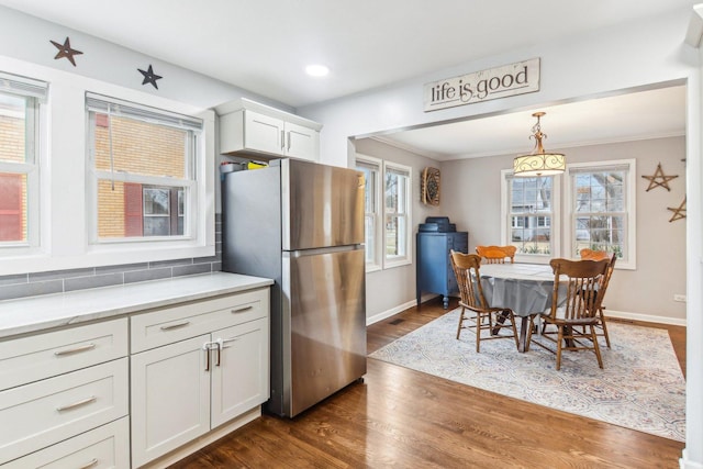 kitchen with dark wood-style flooring, baseboards, white cabinets, ornamental molding, and freestanding refrigerator