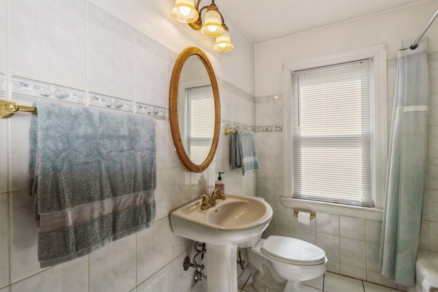 bathroom featuring a wealth of natural light, tile walls, and toilet