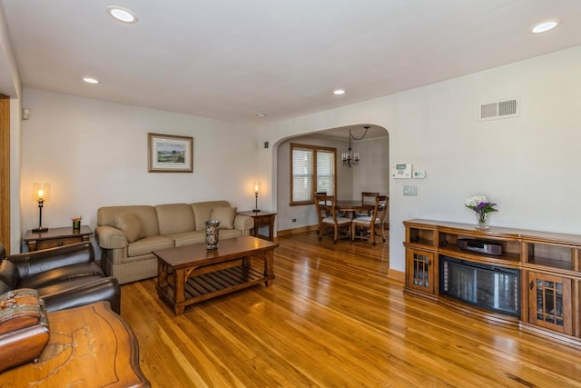 living area featuring arched walkways, recessed lighting, visible vents, wood finished floors, and baseboards