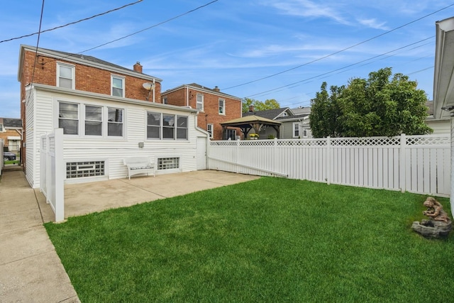 rear view of property featuring fence private yard, a gazebo, a lawn, a chimney, and a patio area