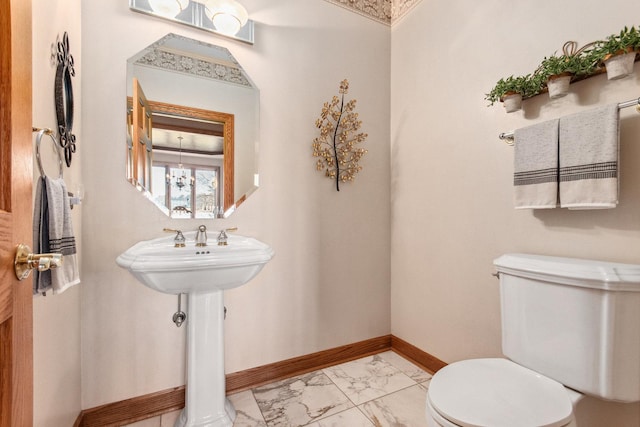 half bath featuring toilet, marble finish floor, baseboards, and a notable chandelier