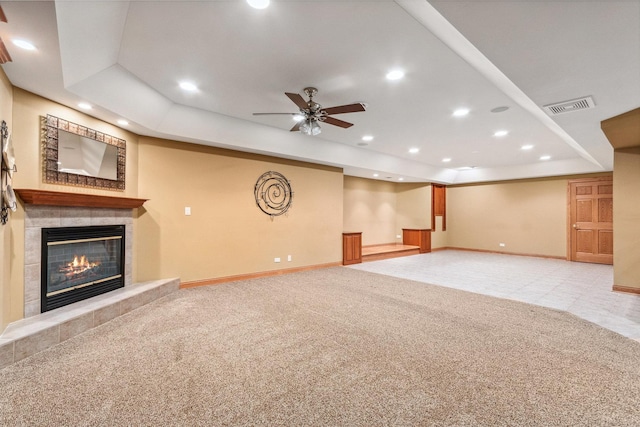 unfurnished living room featuring a tray ceiling, a tile fireplace, carpet flooring, and visible vents