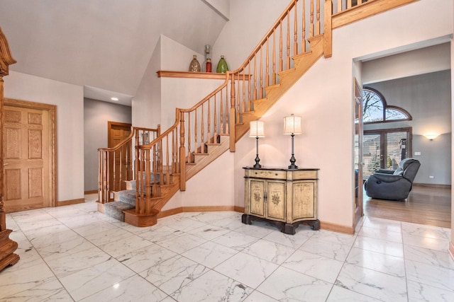 interior space with marble finish floor, baseboards, and a high ceiling