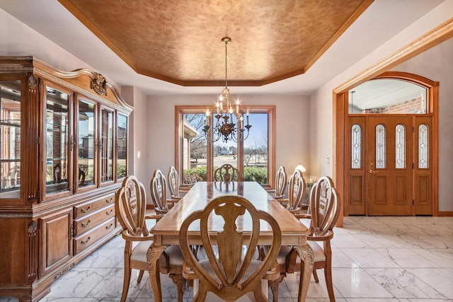 dining area featuring a chandelier, marble finish floor, a raised ceiling, and baseboards