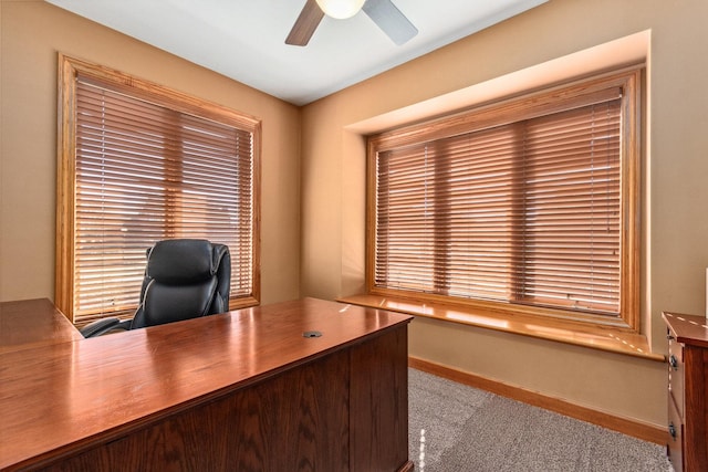 unfurnished office featuring a ceiling fan, carpet flooring, and baseboards