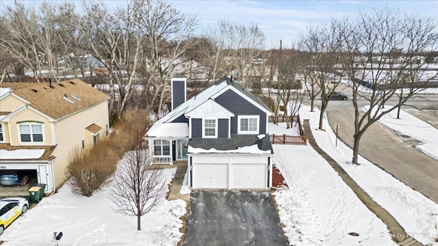 view of front facade with a garage, driveway, and a chimney