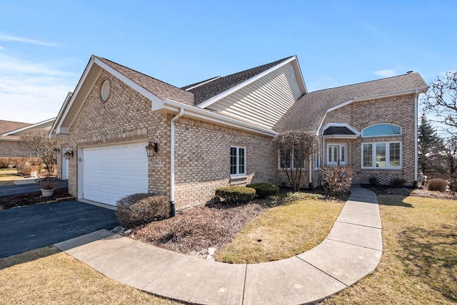 ranch-style home featuring a front lawn, driveway, roof with shingles, an attached garage, and brick siding