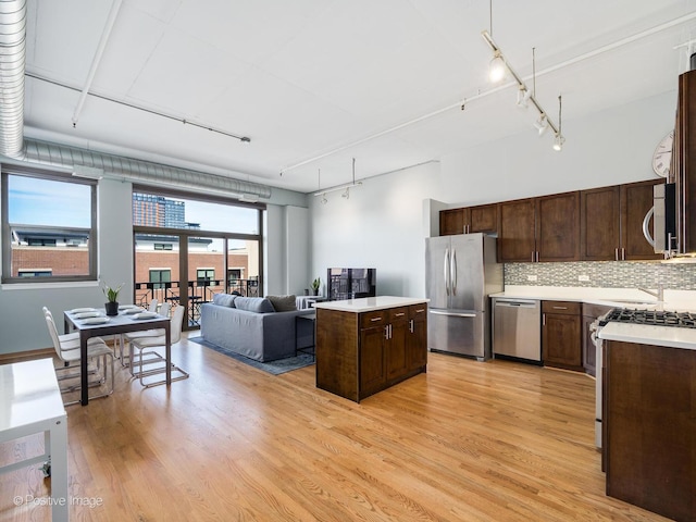 kitchen featuring a kitchen island, stainless steel appliances, dark brown cabinetry, track lighting, and backsplash