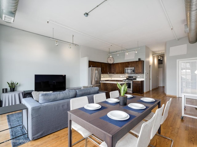 dining room with track lighting, a high ceiling, and light wood-type flooring