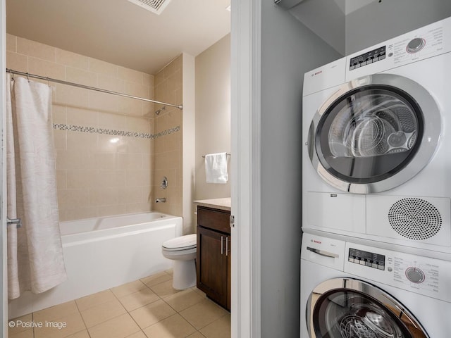 laundry area with stacked washer and dryer, laundry area, and tile patterned flooring