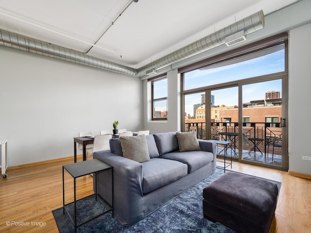 living room with a city view, visible vents, baseboards, and wood finished floors