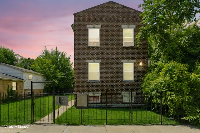 view of front facade featuring a lawn, brick siding, a fenced front yard, and a gate