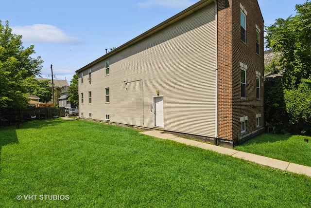 view of property exterior with fence and a lawn