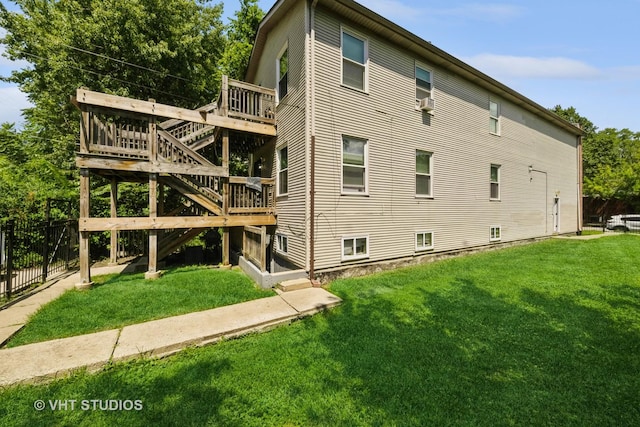 view of side of property featuring fence, a lawn, and a wooden deck