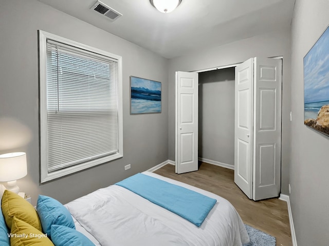 bedroom featuring light wood-style floors, a closet, visible vents, and baseboards