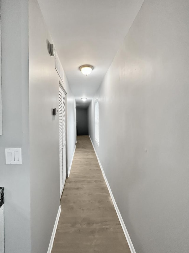 corridor featuring light wood-style flooring and baseboards