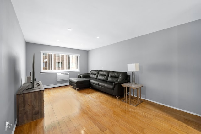 living room featuring hardwood / wood-style flooring, a baseboard radiator, baseboards, and an AC wall unit