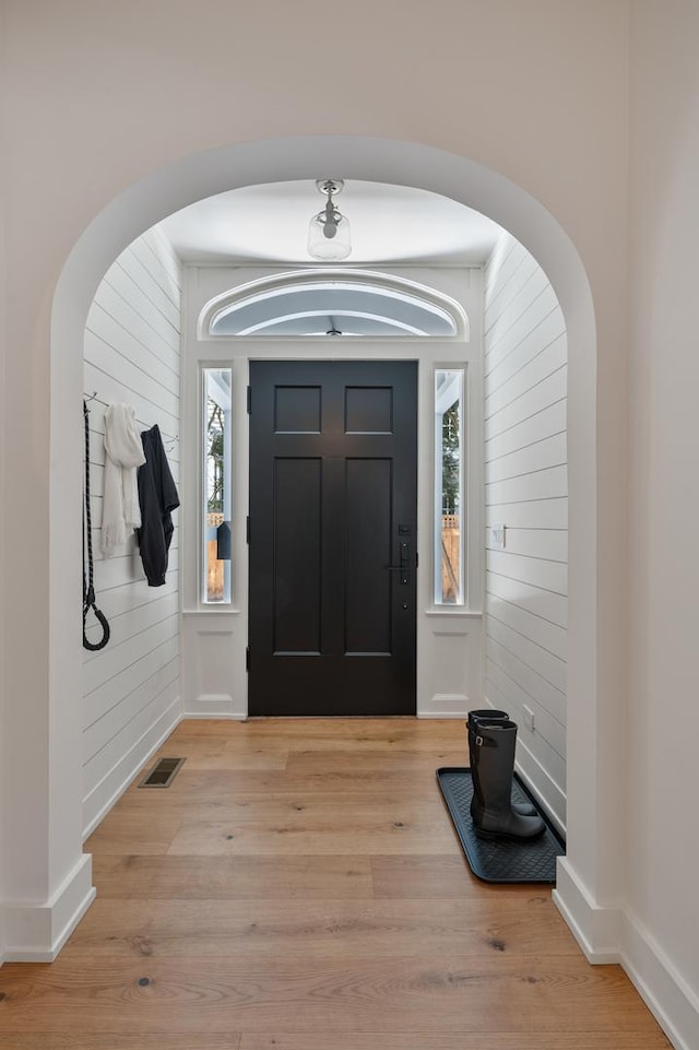 entrance foyer with light wood-style flooring, visible vents, and arched walkways