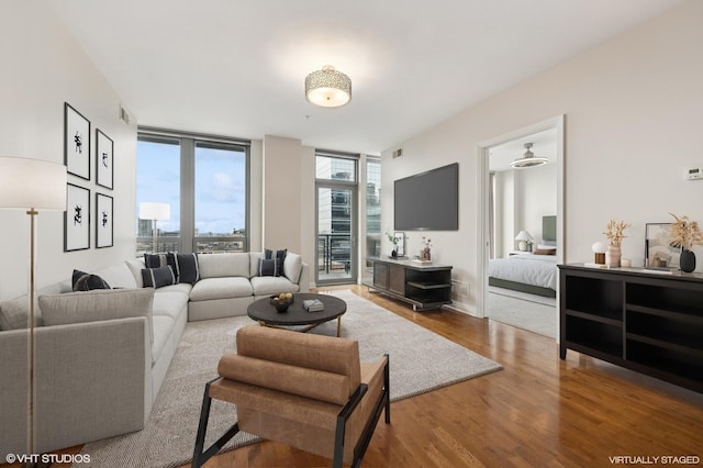 living room with visible vents, baseboards, wood finished floors, and floor to ceiling windows