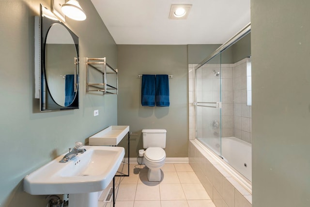 full bath featuring tiled shower / bath, toilet, a sink, tile patterned flooring, and baseboards