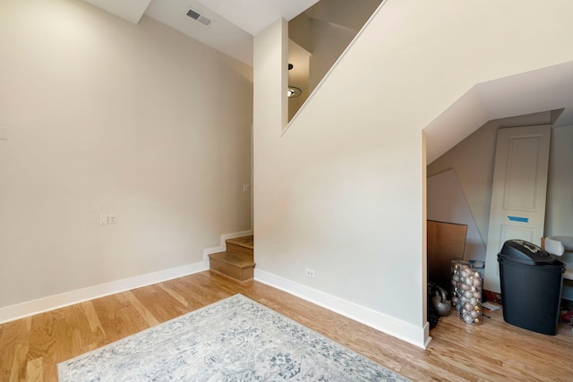 unfurnished room featuring lofted ceiling, visible vents, baseboards, and wood finished floors