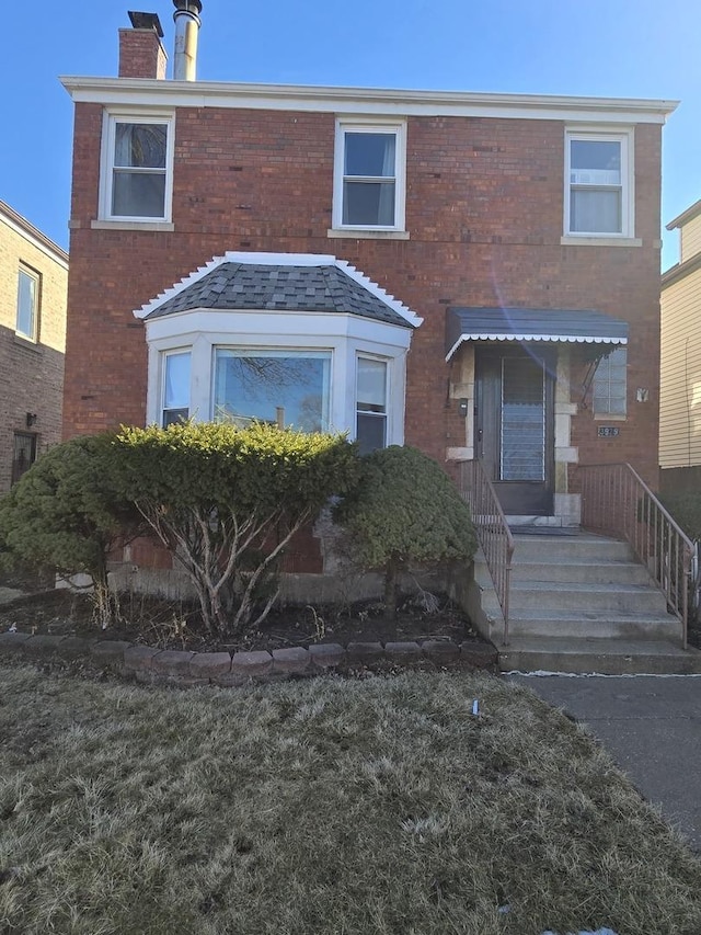 view of front of property featuring a chimney and brick siding