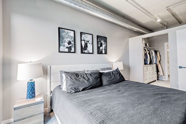 carpeted bedroom featuring rail lighting and a spacious closet