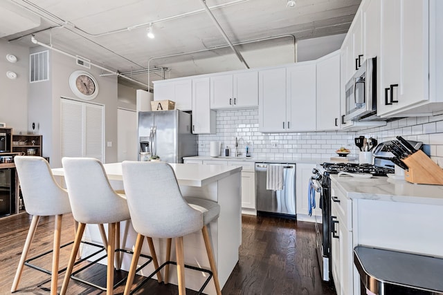 kitchen featuring visible vents, white cabinets, dark wood-style floors, appliances with stainless steel finishes, and a breakfast bar area