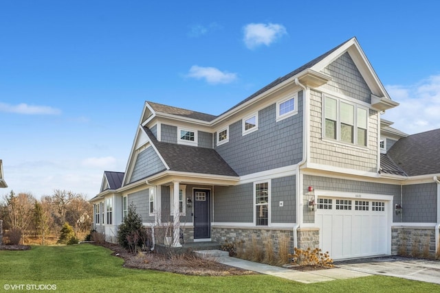 shingle-style home featuring a garage, driveway, stone siding, roof with shingles, and a front yard