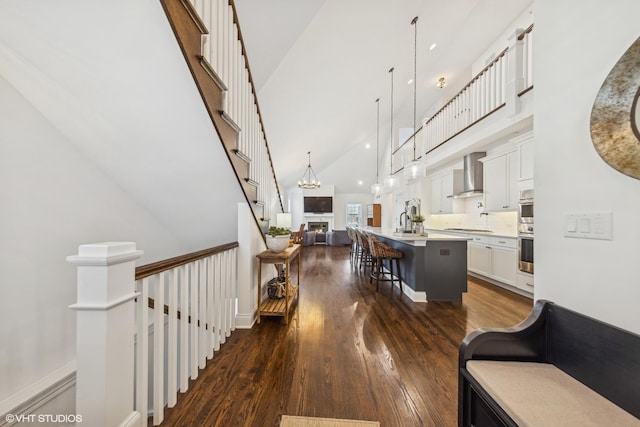 interior space with a notable chandelier, a high ceiling, dark wood-type flooring, a sink, and an upstairs landing