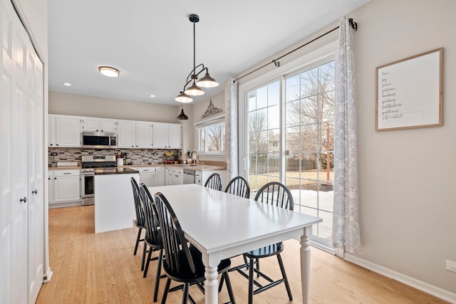 dining area with light wood-style floors, recessed lighting, and baseboards