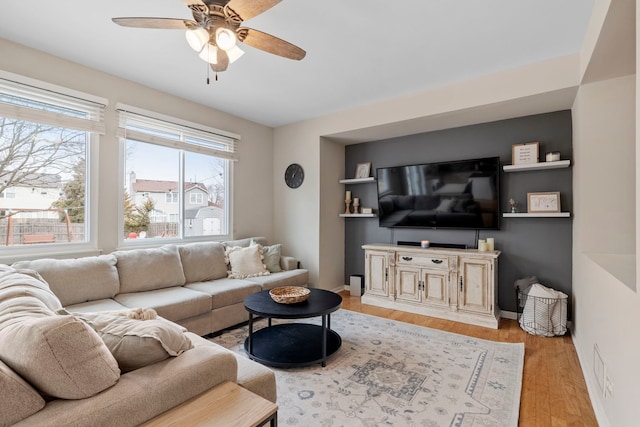 living room with baseboards, ceiling fan, and light wood-style floors