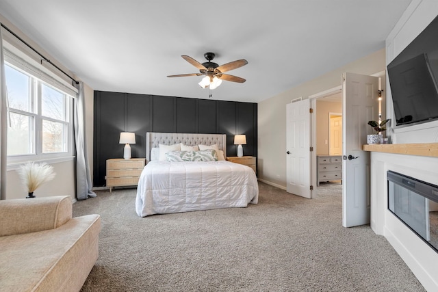 bedroom featuring ceiling fan, carpet floors, a glass covered fireplace, and baseboards