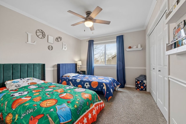 bedroom featuring baseboards, a ceiling fan, crown molding, carpet flooring, and a closet